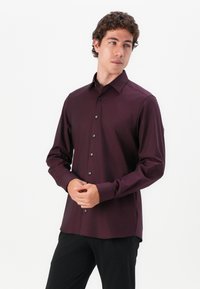 Burgunderfarbendes Langarmhemd mit strukturiertem Muster, Knopfleiste und kontrastierenden dunklen Knöpfen. Slim Fit mit einem mittleren Kentkragen.