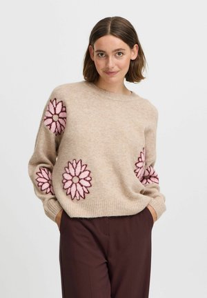 Pull en laine beige avec des motifs floraux roses et bourgogne foncé sur les épaules. Encolure ronde et poignets côtelés, coupe décontractée.