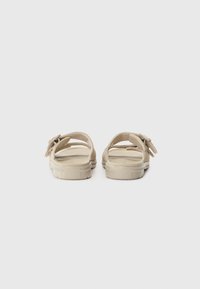 Beige sandaler med mykt semsket skinn, åpen design og gummisåler. Har justerbare remmer for sikker passform og logodetalj på sålen.