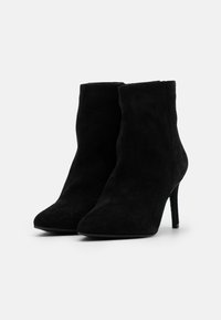 Czarne zamszowe botki za kostkę z ostrym noskiem, wysokim obcasem typu stiletto i gładką teksturą; minimalny design bez ozdób.
