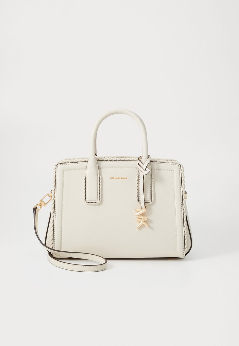 Piccola borsa a tracolla in pelle color crema con due manici, tracolla removibile, charm con logo dorato e dettagli intrecciati lungo i bordi.