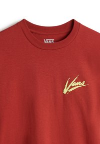 Camiseta de algodón roja con un logo amarillo de Vans en el lado izquierdo del pecho. Cuello redondo y mangas cortas con una textura suave.