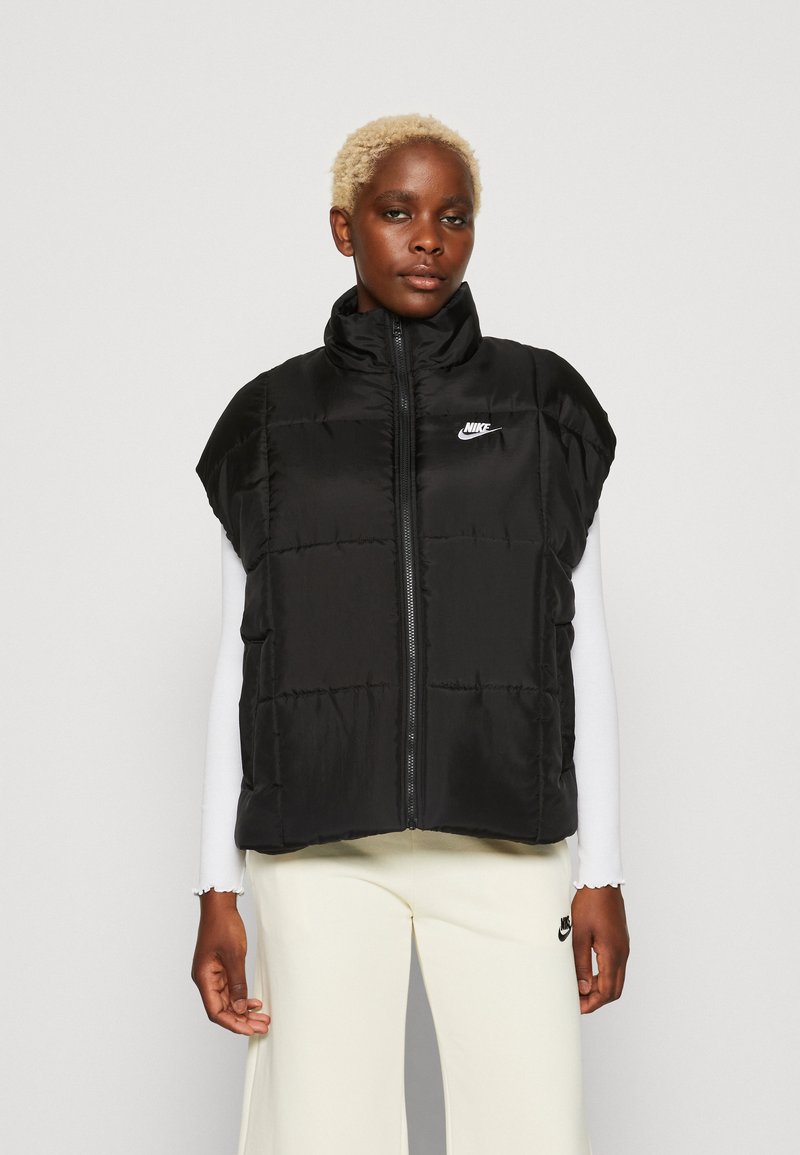 Černá bezrukávová péřová vesta s vysokým límcem, zipovým uzavíráním a předními švy. Obsahuje malé bílé logo Nike na hrudi.