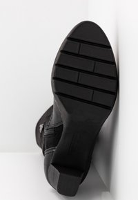 Stivale alla caviglia nero con tomaia in suede testurizzato, zip laterali e suola in gomma con scanalature orizzontali per una migliore aderenza.