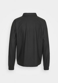 Black long-sleeve shirt with a collar, featuring a smooth texture and gathered cuffs. Back view shows minimal seams and a simple design.