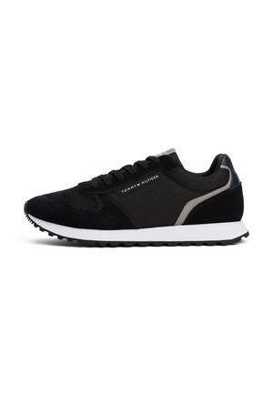 Baskets de course noires avec semelle blanche, dessus en mesh et daim, et logo Tommy Hilfiger sur le côté et le talon.