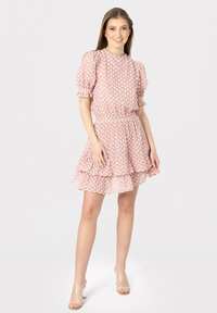 Rochie roz cu buline, cu talie strânsă, mâneci puff și poale cu volane stratificate. Fabricată dintr-un material ușor, cu textură transparentă.
