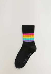 Calcetín de algodón negro con una parte superior acanalada que presenta rayas horizontales en rosa, naranja, amarillo, verde, azul y púrpura. El texto en la parte inferior dice "Pajarito".