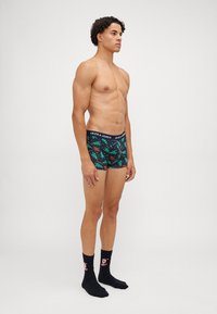 Sötétkék háttérrel rendelkező boxer alsók, élénk zöld fák mintázattal és narancssárga kiegészítőkkel. Rugalmas derékpánt "JACK & JONES" márkázással.