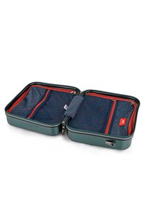Maleta dura verde con acentos de cremallera roja; el interior presenta un forro de tela azul con un patrón ondulado y múltiples compartimentos con cremallera.