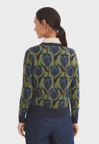 Strickpullover mit grünem Fundament, versehen mit einem floralen Muster in Blau und Mahagoni, mit geripptem Kragen sowie einem dunkelblauen Saum und Bündchen.