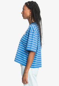 Blue and white striped t-shirt with short sleeves, a loose fit, and round neckline. Material appears soft cotton with a casual design.