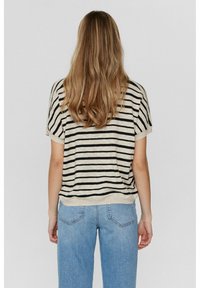 Randig kortärmad topp i beige och svart, med en löst sittande passform och mjuk textur. Matchas med blå denimjeans, vilket ger en avslappnad stil.