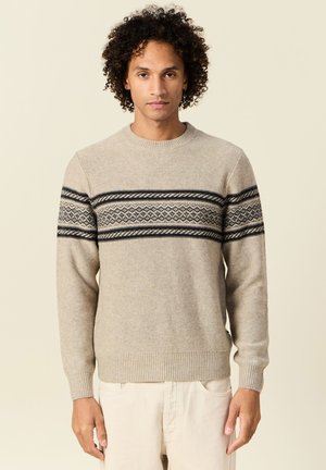Suéter de punto beige con un patrón geométrico en blanco y negro en el pecho, puños y dobladillo acanalados, y cuello redondo.