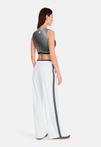 Black and white dotted crop top paired with white wide-leg pants featuring black side stripes, showcasing a sporty design and stretchy fabric.