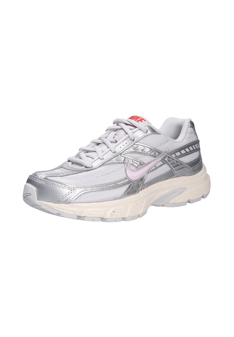 Zapatilla de correr plateada con parte superior sintética, textura de malla, logo de Nike en rosa, cuello acolchado y suela de goma con una entresuela blanca gruesa.
