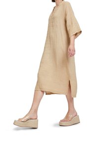 Beige liinakeelne kleit lühikeste varrukatega, V-kaelusega ja külje lõigetega, koos läbipaistvate kiilkingadega, millel on punutud talla. 