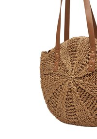 Borsa a mano rotonda in paglia intrecciata di colore marrone chiaro con un motivo geometrico testurizzato. Presenta manici in pelle e dettagli decorativi in metallo.