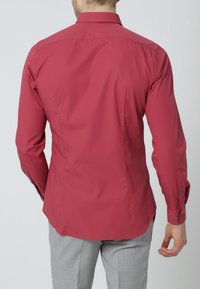 Bordeauxrotes Langarmhemd mit schmaler Passform, verbreitetem Kragen und geknöpften Manschetten. Glatter Stoff mit dezentem Glanz, mit einem maßgeschneiderten Rückendesign.