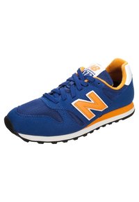 Blå och orange New Balance-sneakers med ovandel i nät och mocka, vit och orange sula, samt snörning.
