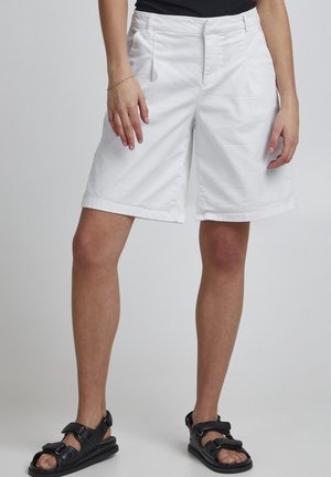 Hvide bomuldsshorts med en afslappet pasform, foran lommer og en foldet kant. Sammen med sorte justerbare sandaler.