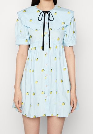 Robe bleu clair avec un large col, des manches courtes bouffantes et des broderies de citrons jaunes. Comprend des boutons sur le devant et un nœud en ruban noir.