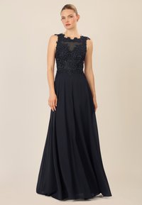 Abito da sera blu navy con un corpo aderente decorato con perline intricate e ricami floreali, che si apre in una gonna fluida. Design senza maniche.