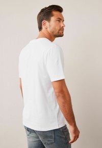 T-shirt en coton blanc à manches courtes, col rond et coupe décontractée, associé à un jean en denim bleu. Design simple et épuré.