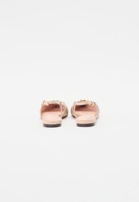 Rosa lær sandaler med ankelremmer og gullfargede spenner, flat såle, åpne tær, glatt tekstur.