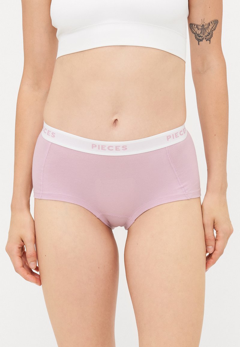 Fioletowe bawełniane majtki z białym pasem, na którym widnieje nazwa marki "PIECES" w jasnoróżowym kolorze. Gładka tekstura, dopasowany krój i styl hipster.