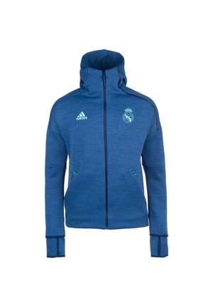 Sweat à capuche bleu zippé avec le logo Adidas sur la poitrine gauche et l'emblème du Real Madrid sur la poitrine droite, avec des trous pour les pouces sur les manches.