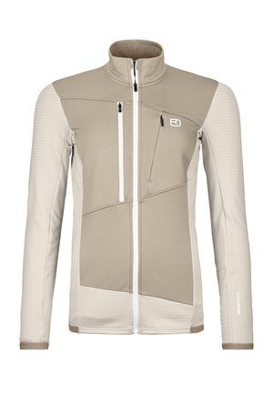 Beige and light cream softshell jacket with a high collar, zippered pockets, textured patterns, and contrasting panel design.