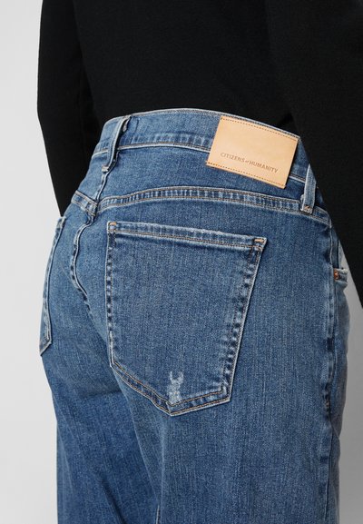 Blaue Denim-Jeans mit mittlerem Waschgang, ausgestattet mit einem Leder-Logo-Patch, Gesäßtaschen und dezenten Ausbleichungen.