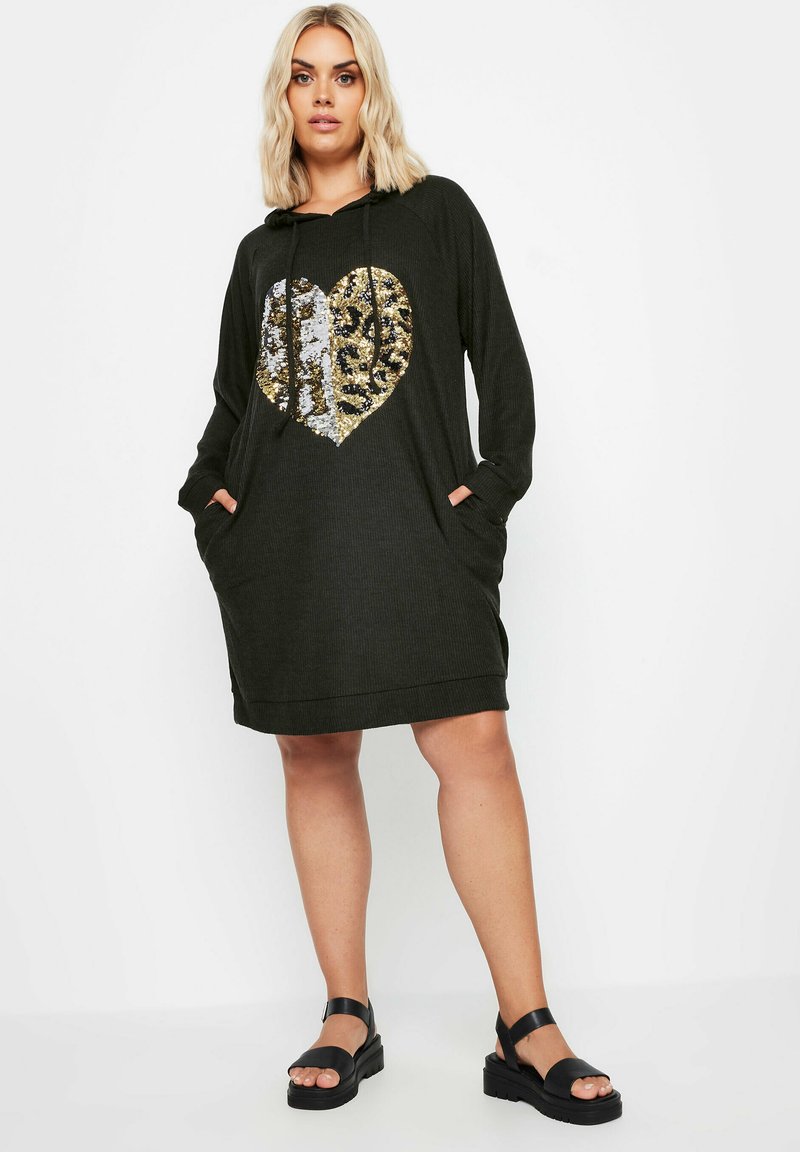 Svart långärmad klänning med huva, prydd med ett hjärtformigt mönster av guld- och silverpaljetter. Klänningen har en avslappnad passform och framfickor.