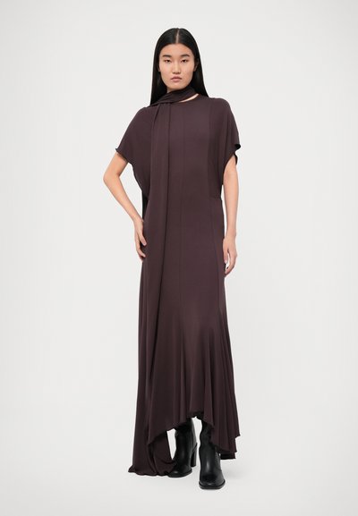 Long, deep burgundy dress with loose short sleeves, a draped neckline, and asymmetrical hem, paired with black ankle boots. Smooth fabric texture.