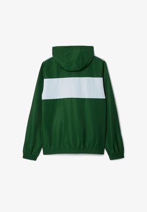 Chaqueta verde con capucha y una franja horizontal blanca en la parte posterior, con puños y dobladillo elásticos, tejido suave y corte regular.