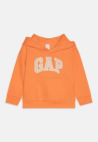 Oranžová mikina s kapucí a přední kapsou, s nápisem "GAP" v béžovém písmu. Vyrobená z měkké bavlny, má žebrované manžety a lem.