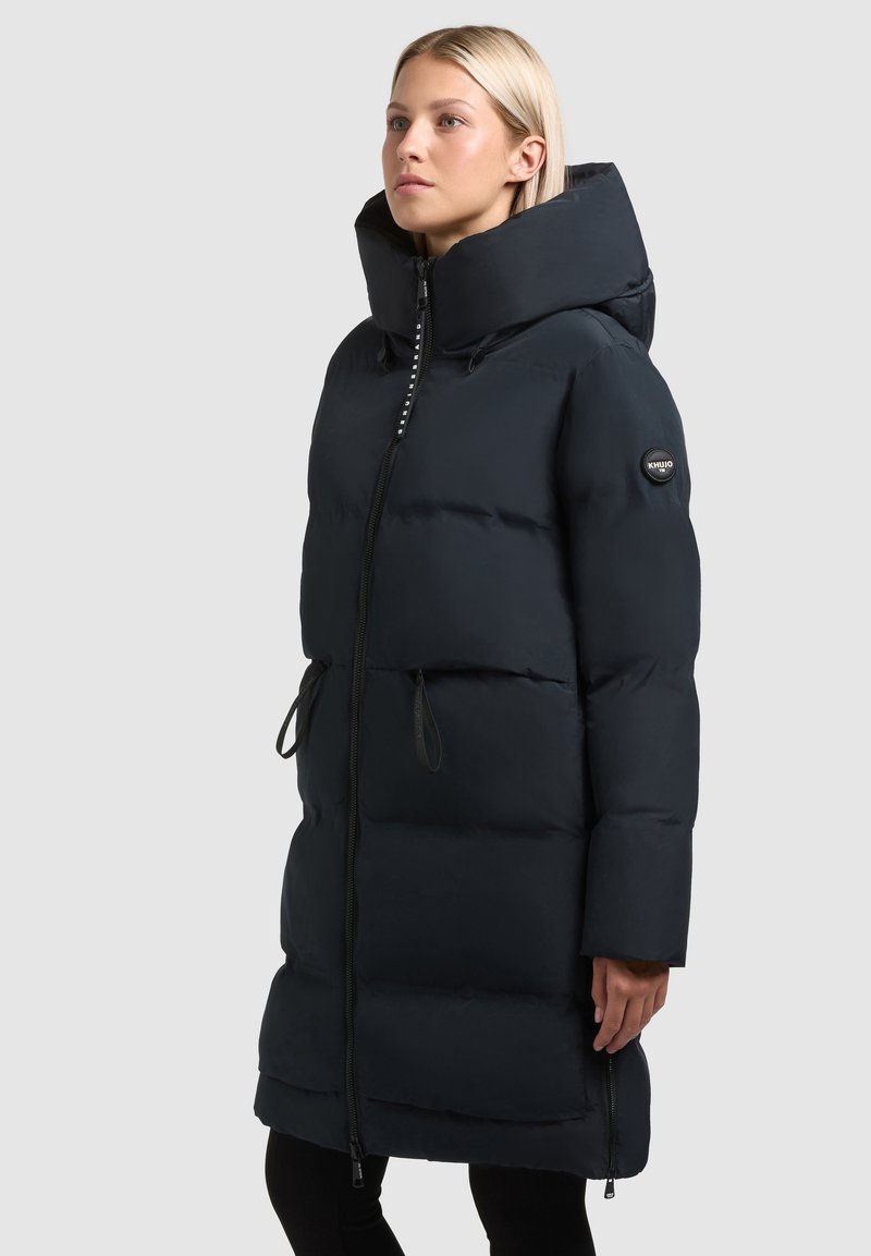 Jūras spēku pūkains mētelis ar augstu apkakli, priekšējo rāvējslēdzēju un sānu kabatām. Iezīmējas ar quilted tekstūru un auklām jostas vietā, kas ļauj pielāgot piegriezumu.