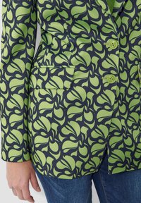 Blazer met een donkere achtergrond en een levendig groen Abstract bladerenpatroon, twee knopen en een enkele borstzak.