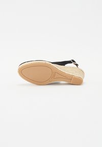 Černé espadrilky s pletenou juteovou patou, gumovou podrážkou a nastavitelným popruhem. Disponují texturovanou plochou podrážkou pro stabilitu a pohodlí.