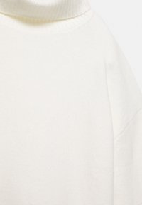 Witte coltrui met een ribgebreide kraag, zachte textuur en een relaxte pasvorm met verlaagde schouders. Eenvoudig en minimalistisch ontwerp.