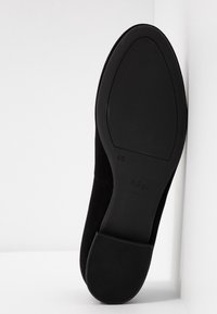 Semelle de chaussure plate noire avec un petit talon, indiquant la taille 4 1/2 et la marque "högl" sur un fond blanc.