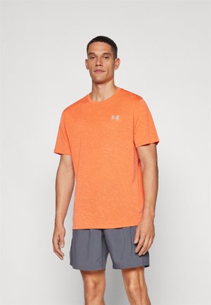 Oranž spordit-särk, millel on tekstureeritud muster, ümar kaelus ja lühikesed varrukad. Rindkerel on väike hall logo. Kombineeritud hallide lühikeste pükstega.
