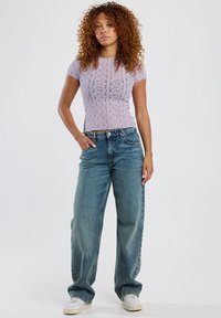 Light purple lace top with short sleeves paired with loose-fitting blue denim jeans and white sneakers.