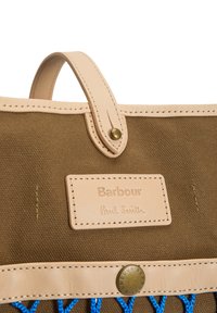 Καφέ τσάντα από καμβά με μπεζ δερμάτινη επένδυση, μπεζ δερμάτινο λουράκι χειρός με ορειχάλκινο κουμπί και ραμμένη μπεζ ετικέτα με την επιγραφή Barbour Paul Smith.
