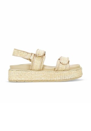 Sandalias de paja tejidas en beige con tiras ajustables, suela de plataforma y un acabado texturizado, que cuentan con plantillas planas y acolchadas.