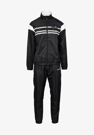 Survêtement noir comprenant une veste zippée avec des rayures blanches et un pantalon assorti. Fabriqué en matériau synthétique lisse avec des poignets élastiques.