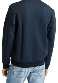 Sudadera azul marino con cuello y puños acanalados, confeccionada en una tela suave, con un corte relajado y sin logotipos visibles.