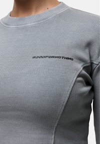 Top grigio a maniche lunghe con costine, caratterizzato da un collo rotondo e dettagli nelle cuciture laterali, con il testo "GOODFORNOTHING" ricamato in nero.