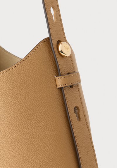 Sac à main en cuir tan avec une surface texturée, présentant un détail de bouton doré et une bandoulière ajustable avec plusieurs trous.